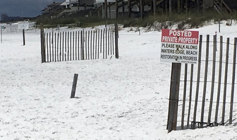 Sign directs beachgoers to walk along the water's edge.
