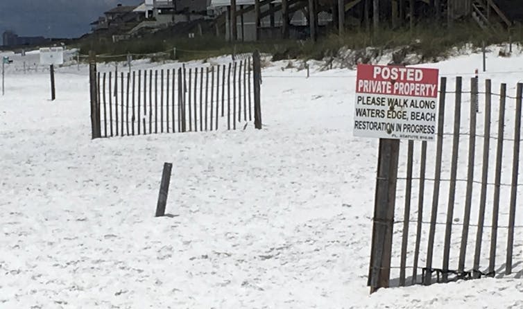 Sign directs beachgoers to walk along the water's edge.