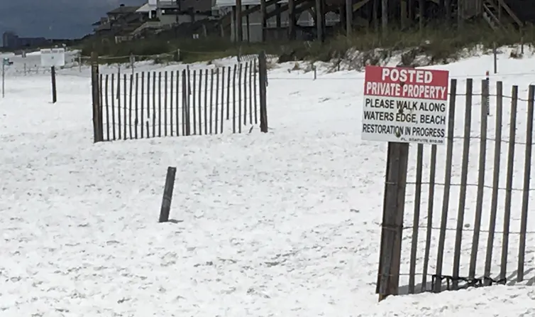 Sign directs beachgoers to walk along the water's edge.