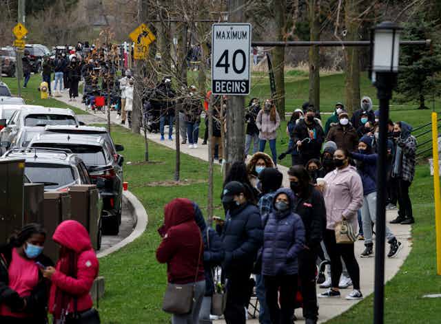 Hundreds of people lined up along a sidewalk waiting for vaccinations