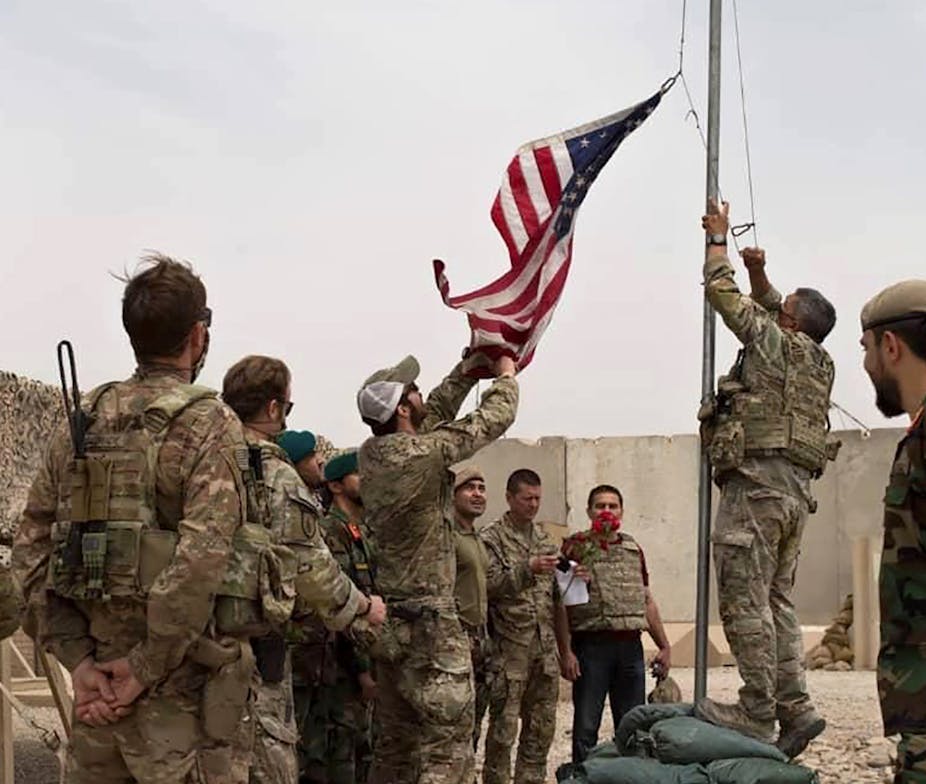 A U.S. flag is lowered as American and Afghan soldiers attend a handover ceremony from the U.S. Army to the Afghan National Army, at Camp Anthonic, in Helmand province, southern Afghanistan, Sunday, May 2, 2021.
