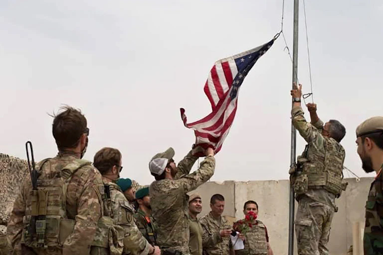 A U.S. flag is lowered as American and Afghan soldiers attend a handover ceremony from the U.S. Army to the Afghan National Army, at Camp Anthonic, in Helmand province, southern Afghanistan, Sunday, May 2, 2021.