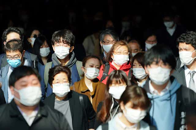 Crowd of people wearing medical face masks.