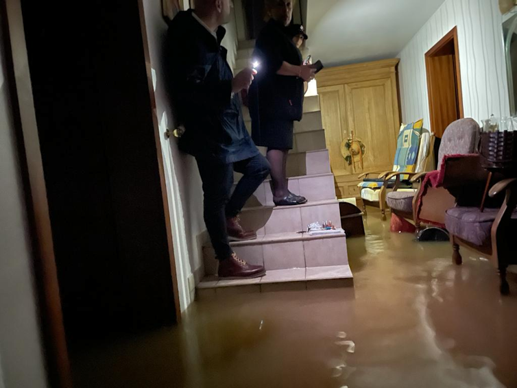 Two people stand on a staircase beset by rising water.