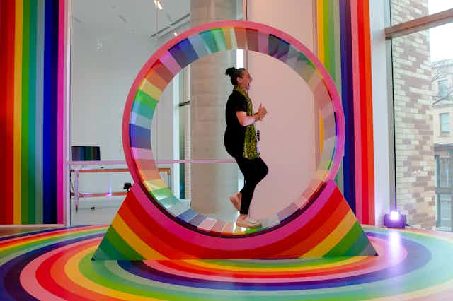 woman runs inside colourful wheel