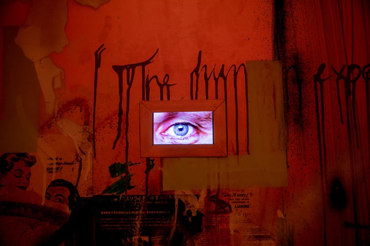 Dark red room with projected eye ball on wall