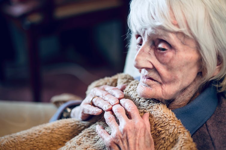 older woman clutches blanket