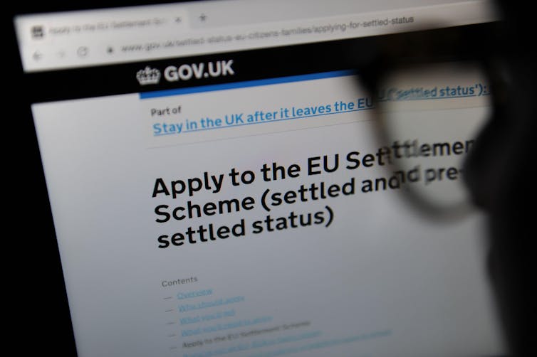 A person in silhouette looking at the webpage for the EU settlement scheme application.