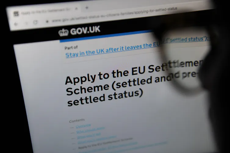 A person in silhouette looking at the webpage for the EU settlement scheme application.