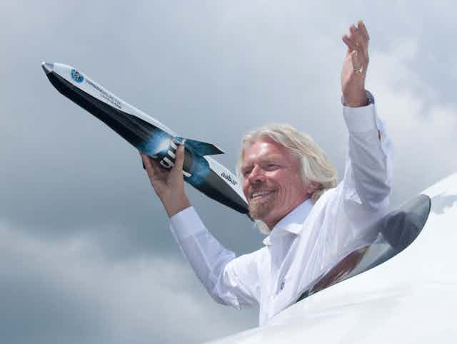 Richard Branson clutching a model Virgin Galactic spaceplane.