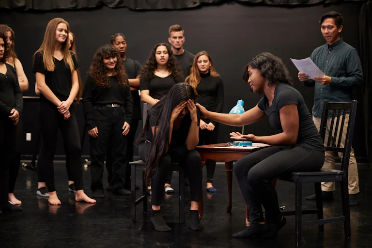 A group of drama students dressed in black take part in an improv class