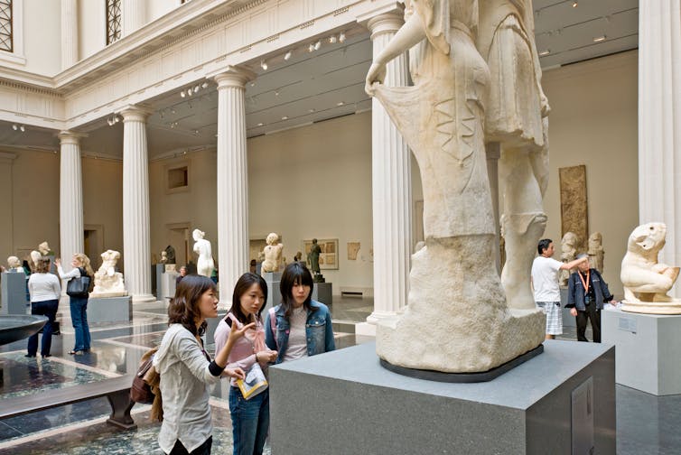 Three students discuss a marble in the New Greek and Roman Galleries at The Metropolitan Museum of Art, New York City