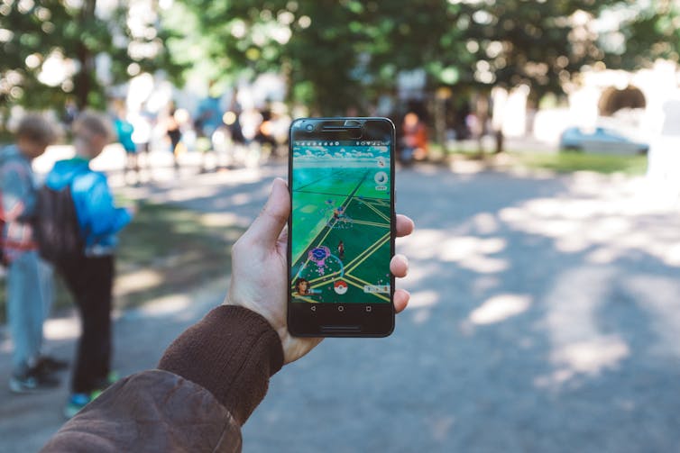 Hand holding up phone playing PokÃ©mon Go