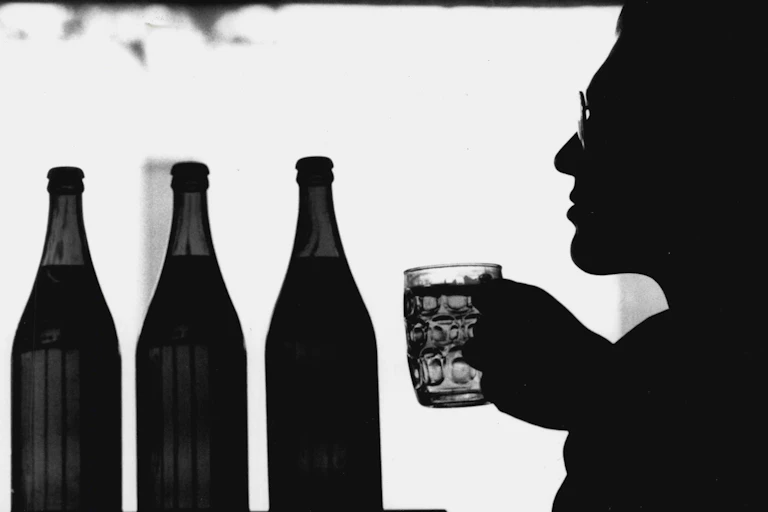 A man drinks a beer out of a mug.
