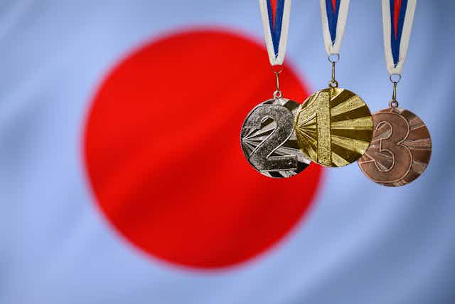 Les trois médailles olympiques placées en premier plan du drapeau du Japon