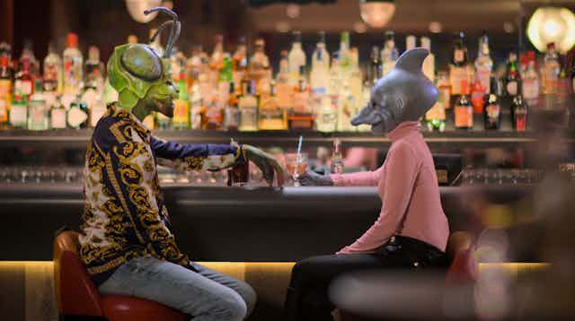 A grasshopper/human and a dolphin/human sit at a bar
