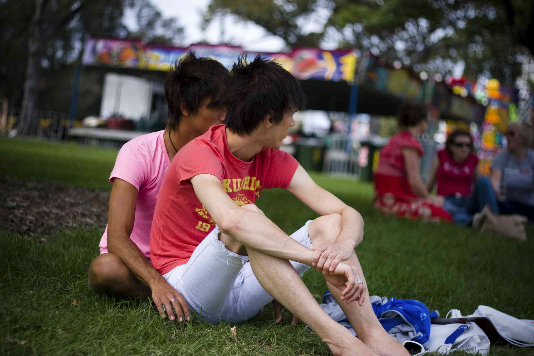 A gay couple sitting on a lawn.