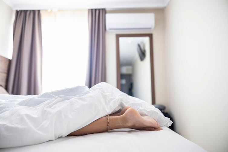 Woman's feet stick out of the end of a bed.