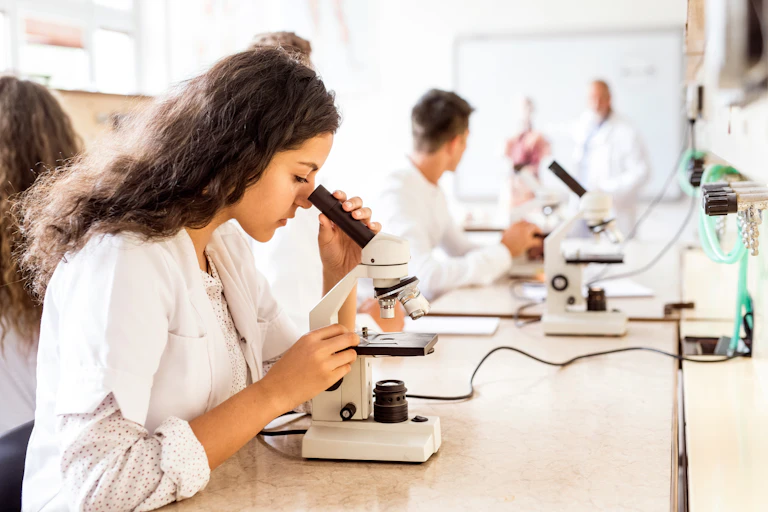 Senior students in lab coats looking through microscopes.