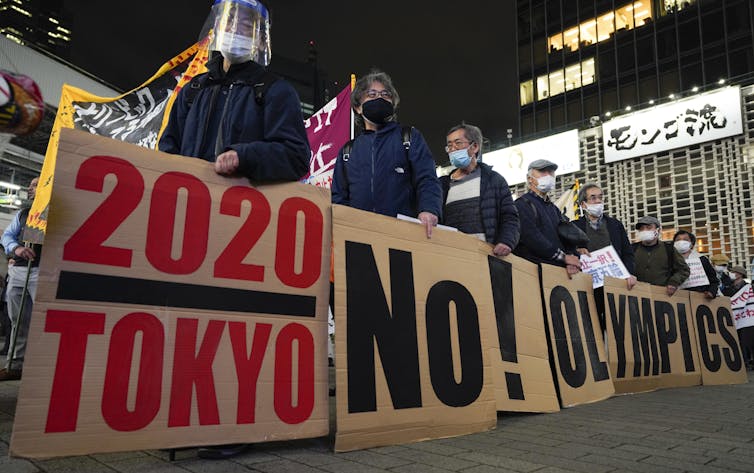 Protestors stand with placards opposing the Games.