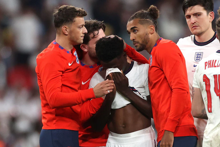 English player Bukayo Saka is comforted by teammates after missing a penalty in the England v Italy final of the Euros 2020