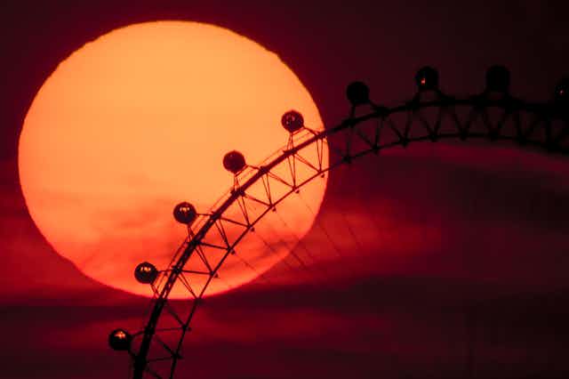The sun sets behind the London Eye.