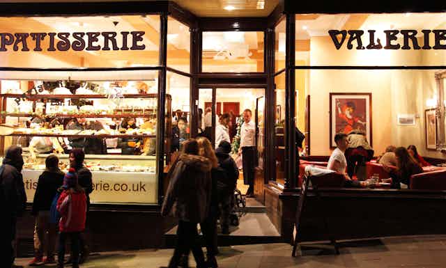 Patisserie Valerie shopfront with customers in the evening