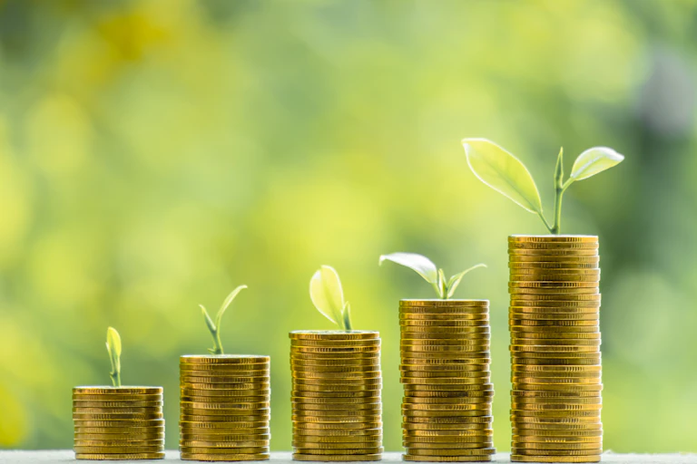Piles of coins with young plants growing behind.