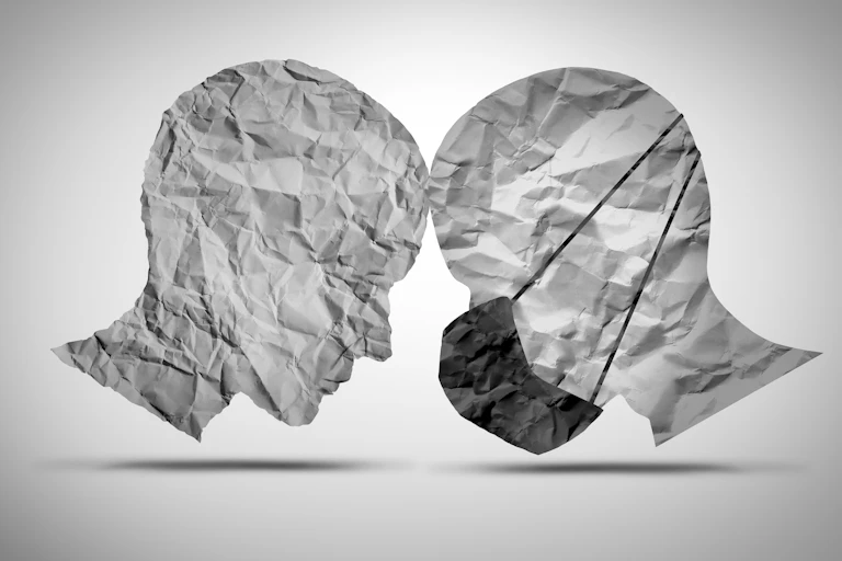 Two paper cut outs of human heads - one wearing a mask, one not.