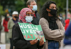 A woman holds a sign that reads Muslim Lives Matter.