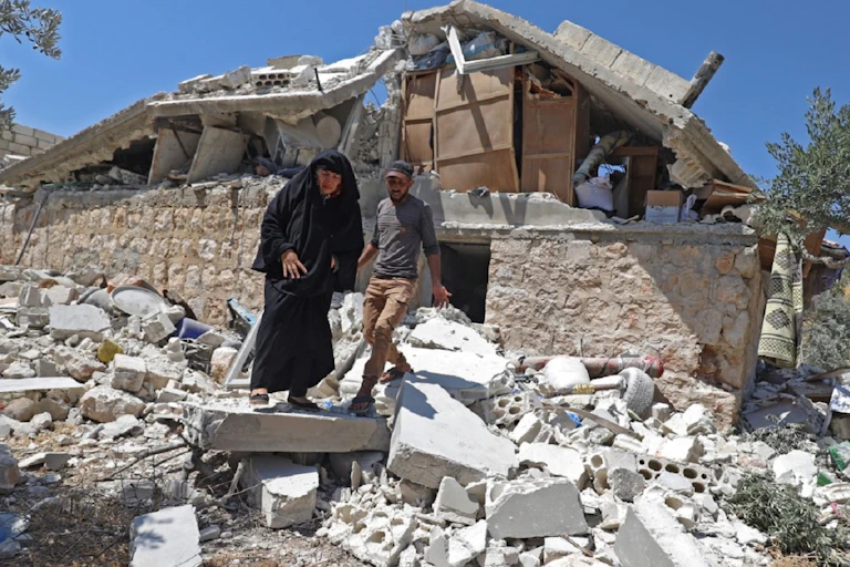 Deux habitants marchent sur les décombres d'une maison, après un bombardement des troupes du régime, à Serja dans la province d'Idlib, le 17 juillet dernier.