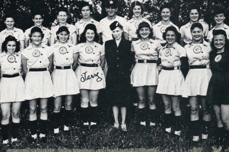 Two rows of women in vintage skirted baseball uniforms.