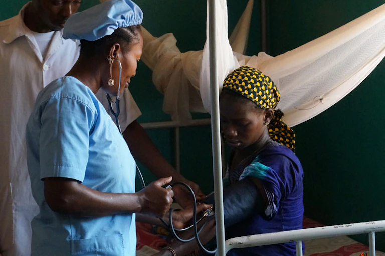 A young Black woman with an infant and two health-care workers