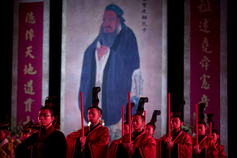 In 2016, participants in traditional dress stand near an oversized portrait of Confucius during a ceremony to observe the 2567th anniversary of his birth in Beijing. China is running five-day Confucian culture immersion courses for religious leaders in the sage's hometown as part of a campaign to extend government control over faith communities through a process of sinicization.
