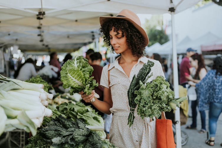 Woman buying kale at the market.