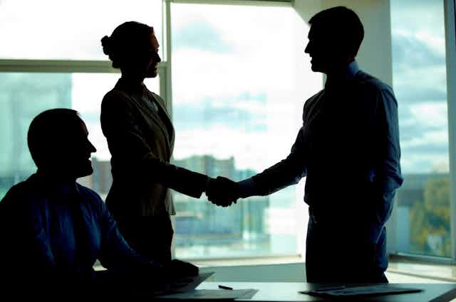 Business people in silhouette shaking hands on a deal