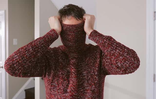 man with turtleneck of sweater pulled over his face