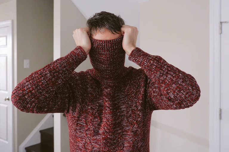 man with turtleneck of sweater pulled over his face