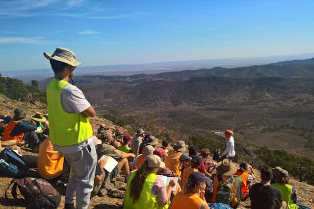 Earth sciences students seated on a hillside during a field trip