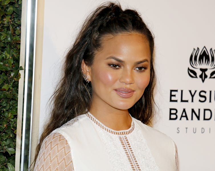 Chrissy Teigen in a white dress with her hair pulled back