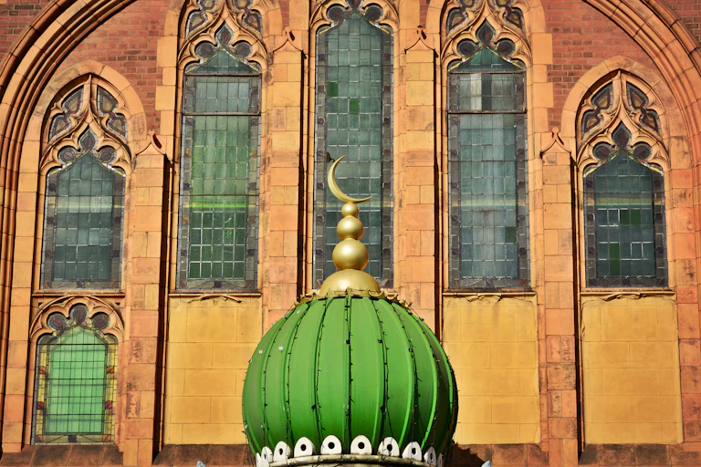 The top of a mosque with the crescent moon sitting in front of a Christian church in the UK.