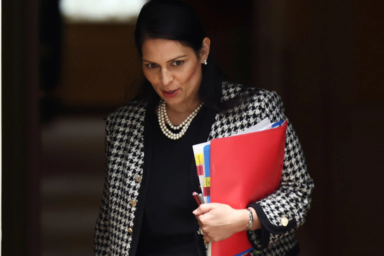 Home secretary Priti Patel carrying folders under her arm.