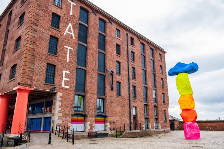 Exterior of Tate Liverpool art gallery in the Albert Dock Area in Liverpool, Merseyside with a colourful outdoor sculpture