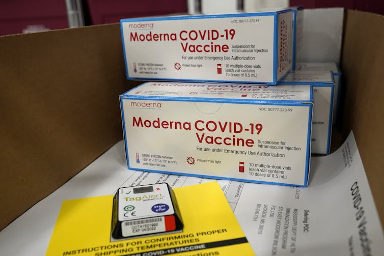 Four boxes of Moderna COVID—19 vaccines sitting on papers.