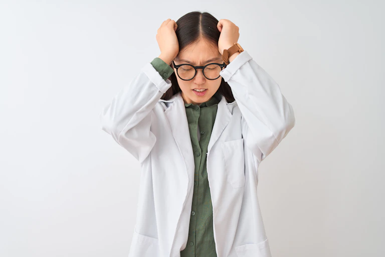 Woman in lab coat holding her head in frustration