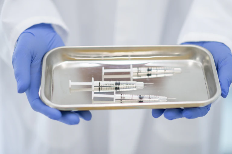 A doctor holding a tray with syringes.