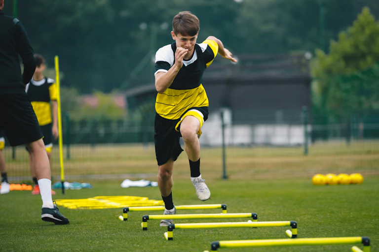 Boy running over obstacles on the field.