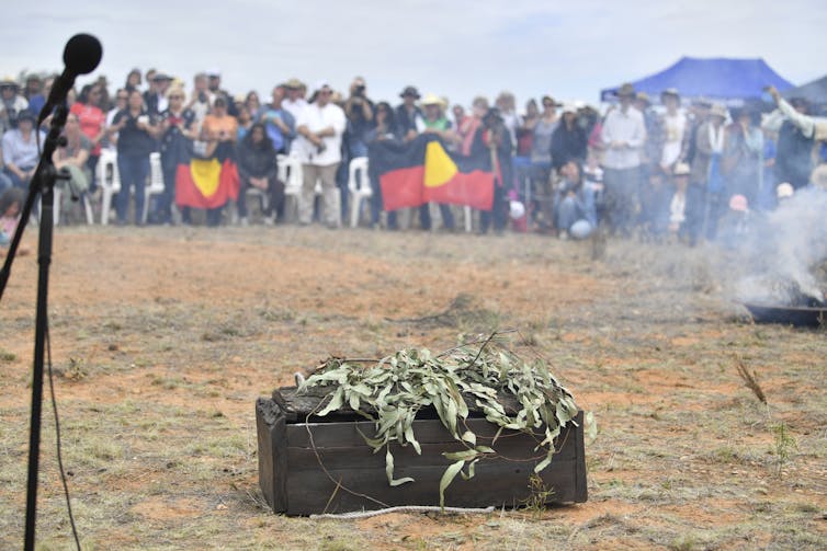 Indigenous ceremony with flag and casket
