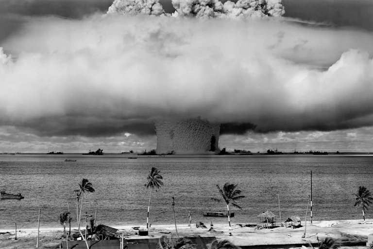 Nuclear mushroom cloud in background, palm beach in fore.