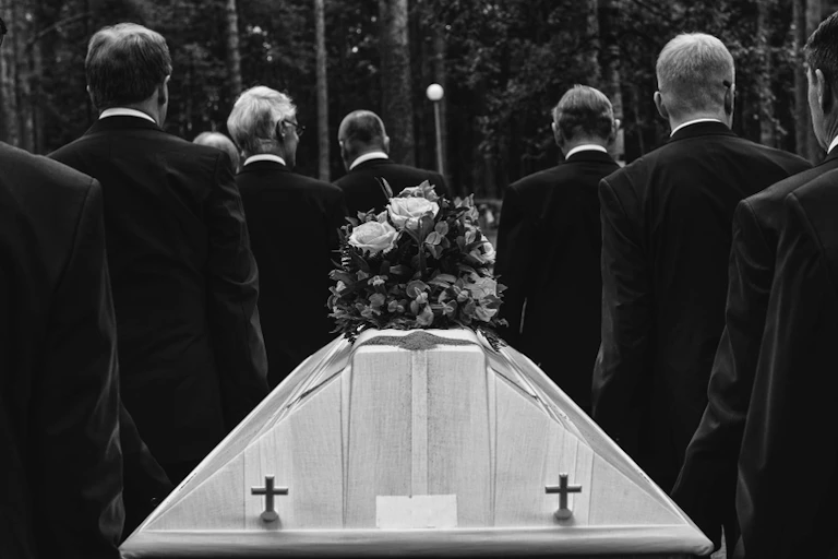 A black and white image of a funeral with eight men carrying the coffin.